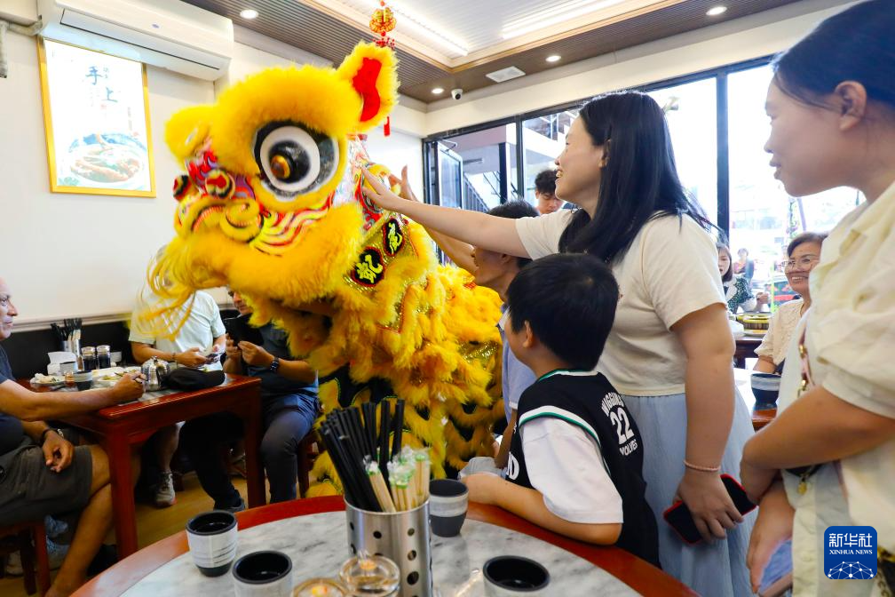 2月17日，在巴拿马首都巴拿马城，舞狮演员在一家中餐馆与顾客互动。新华社发（丹尼尔·冈萨雷斯摄）