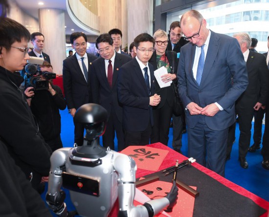 2月26日，德国总理默茨在杭州宇树科技观看机器人写“福”字。新华社记者 翁忻旸 摄